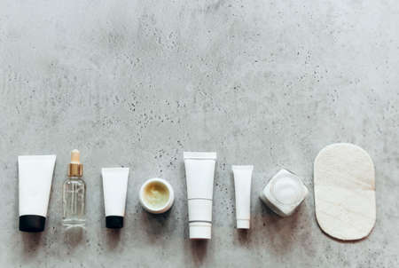 Flat lay of assorted spa tools and cosmetics placed on gray stone surface