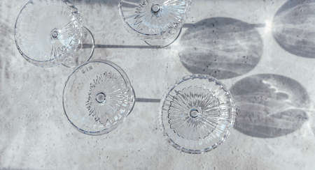 Top view of collection of shiny glass goblets casting shadows on table in restaurantの写真素材
