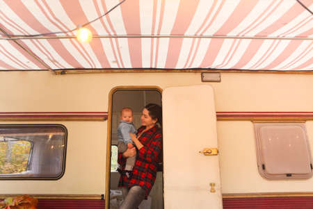 Portrait of the smiling happy mother with baby son in the house on wheelsの写真素材