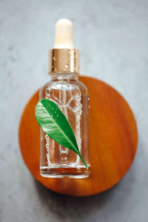 Top view of bottle of essential oil placed on wooden circle with fresh leafの写真素材