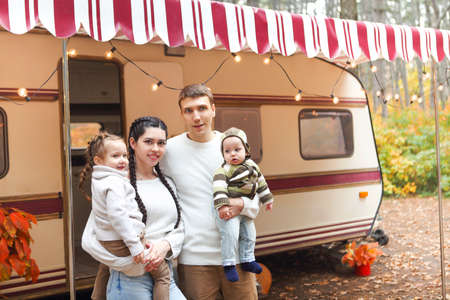 Portrait of a young smiling family while hugging near house on wheels outdoors