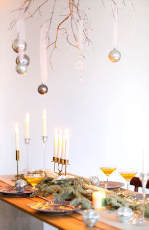 Champagne glasses on wooden table with candles against blurred wall with Christmas decorの写真素材