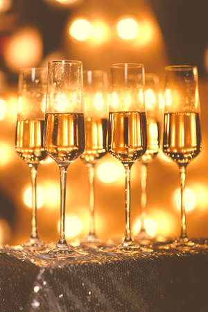 Transparent wineglasses with champagne placed on blurred background of bright illumination during partyの写真素材