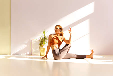 Side view of calm female in sportswear practicing yoga in Firefly pose while balancing with arms on...