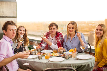 Happy man and woman with alcohol drinks smiling during meeting with friendsの写真素材
