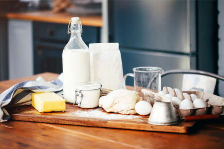 Assorted ingredients for pastry preparation placed on wooden chopping board on table in kitchen