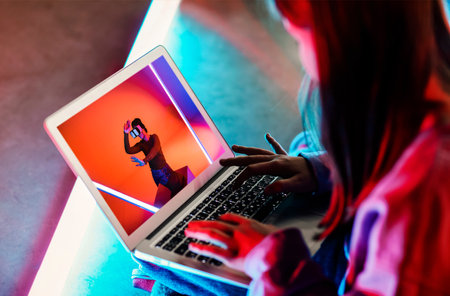 From above crop female browsing and watching video of woman in VR headset on netbookの写真素材