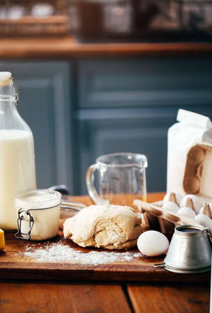 Assorted ingredients for pastry preparation placed on wooden chopping board on table in kitchen. Rustic style. Vertical photoの写真素材
