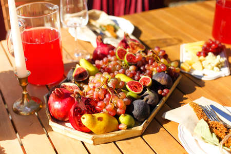 Empty wineglass placed near board with fruits on banquet table on sunny summer day