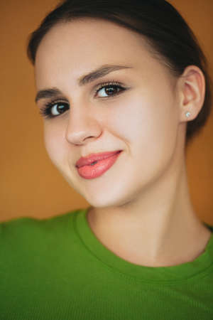 Positive female laughing happily on brown background in studio and looking at camera