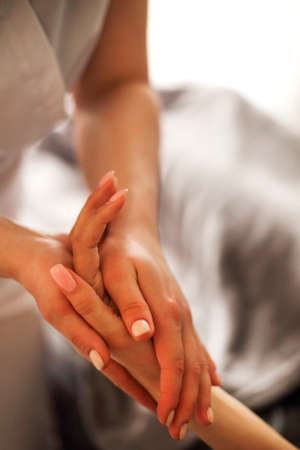 Faceless master massaging arm and wrist of woman lying on table in massage salon