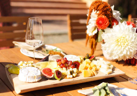 Empty wineglass placed near board with fruits on banquet table on sunny summer dayの写真素材