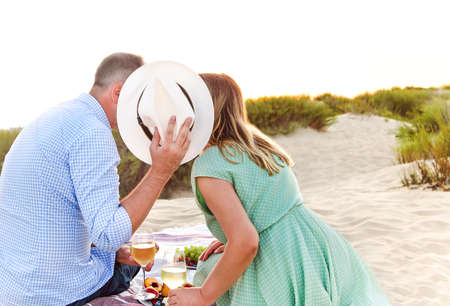 Anonymous man and woman with wineglasses proposing toast over fruits during romantic picnic holding...