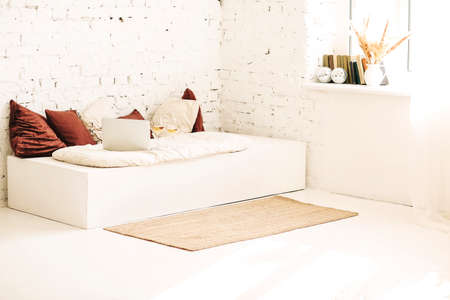 Mat placed near couch with laptop and wine against white brick wall in sunlit room at home