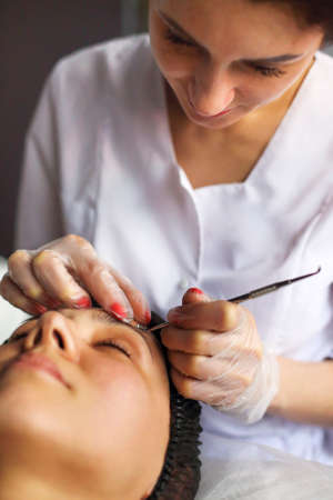 Professional beautician cleansing of acne of woman during anti aging procedure in beauty clinic