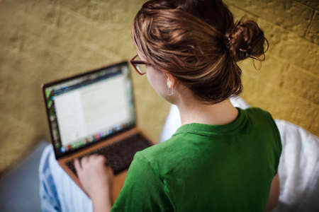 Smiling teen girl having video call on laptop, female using netbook while relaxing at home. Home education and learning conceptの写真素材