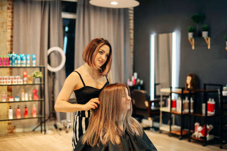 Professional female hairdresser smearing dye on hair of woman while working in beauty salonの写真素材