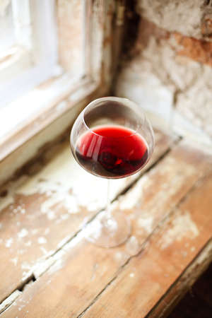 One wineglasse with red wine during party with copy space. Celebration and holiday concept