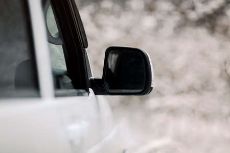 Soft focus of white vehicle with wing mirror parked in snowy countryside in winter
