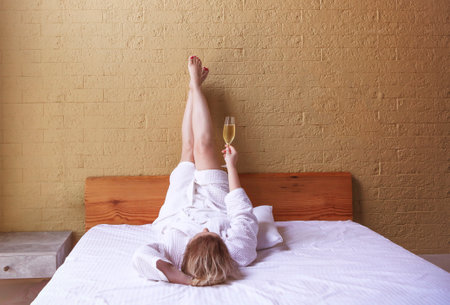 Woman in white robe with a glass of champagne in her hands. Holiday conceptの写真素材
