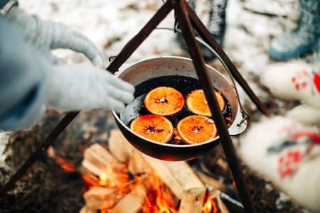 From above traditional mulled wine with slices of orange preparing in pot over burning logs in winter in countrysideの写真素材