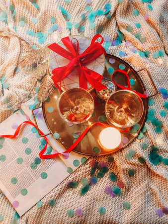 Tray with decorations and gift box placed on comfortable bed in cozy bedroom decorated for Christmas celebration at nightの写真素材