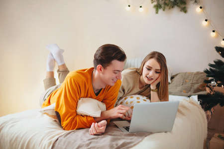 Portrait of smiling happy couple with laptop on sofa at homeの写真素材