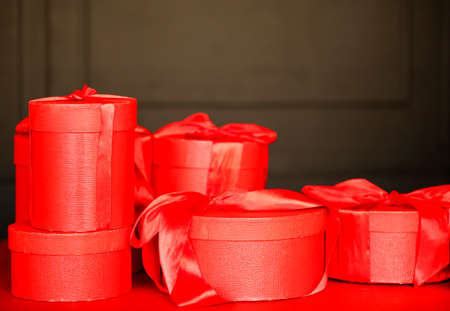 Heap of red gift boxes and golden baubles placed on table against black wall on Christmas dayの写真素材