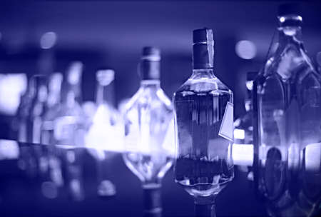 Classic bar counter with bottles in blurred very peri background in the nightの写真素材