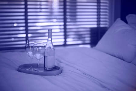 Two glasses of white wine in bed on the blurred very peri background. Copy space
