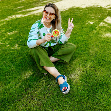 Happy cheerful young woman blowing bubbles with bubble machine and laughing while sitting relaxing...