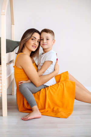 Young happy family loving mother and her child son having fun together at home, playing and laughing. Smiling kid hugging embracing his mom, happy to spend leisure time on weekend with mommyの写真素材