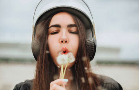 Outdoor portrait of young beautiful woman biker in bike safety helmet and leather outfit with...