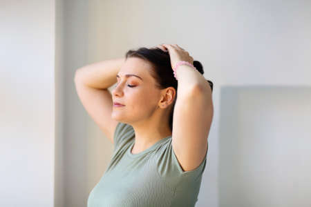 Photo in motion of cheerful young woman, jumping or doing sports indoor, looking back at camera while moving with broad smile, posing against blurred apartment interior backgroundの写真素材