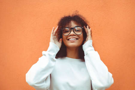 Happy positive young African American girl in eyewear, smiling afro female holding glasses with...