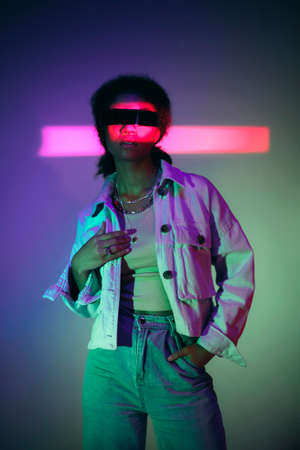 Young confident african american woman wearing VR headset exploring virtual world while standing in...