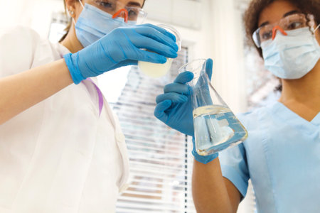 COVID-19 Testing Lab. Two women medical laboratory scientists colleagues wearing face masks working...