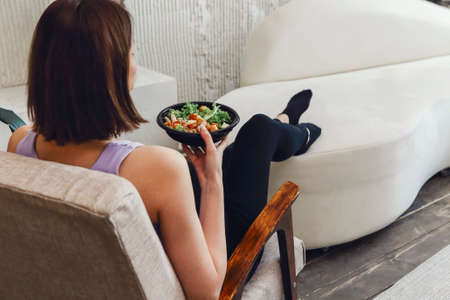 Pregnant young brunette woman eating healthy salad from bowl top view. Healthy food while having...