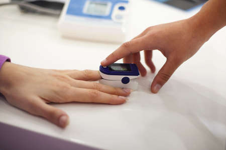 Pregnant woman with pulse oximeter on finger. Doctor measuring oxygen saturation level while...