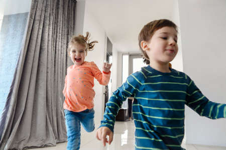 Happy family running in hall. Funny kids jumping with cardboard box, parents laughing, play with...