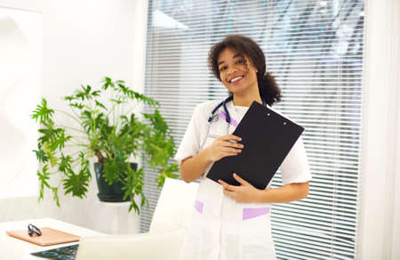 Happy african american female doctor physician wearing medical uniform with stethoscope around neck...