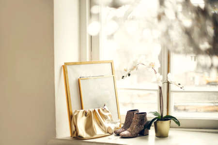 Home mockup with frames close up standing on windowsill with golden accessories and orchid winter evening time in room with chandelierの写真素材