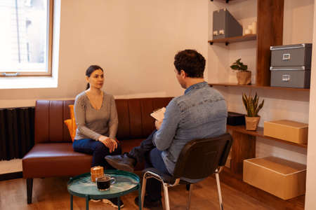 Psychotherapy. Nice serious pleasant woman visiting a psychologist and having a psychological session while dealing with problems in relationshipsの写真素材