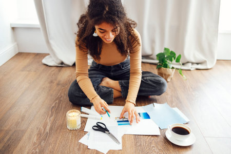 Young brunette african american woman creating her Feng Shui wish map using scissors. Dreams and...