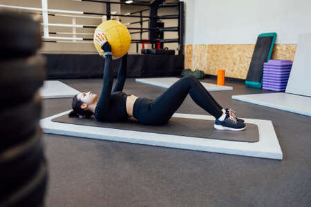 Athletic brunette girl working out in the gym. Fitness woman training with medicine ball