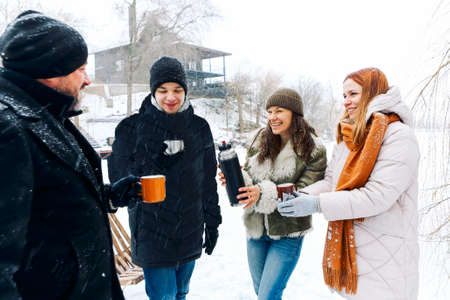 People at winter resort on winter holidays. Friends relaxing, drinking hot coffee. Break after...