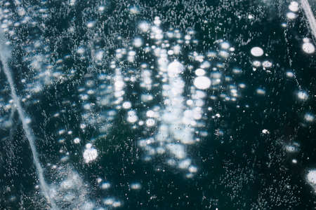 Texture of beautiful blue ice with cracks and air bubbles in the frozen lake. Winter nature abstract background. Lake Baikal, Siberia, Russia.の写真素材