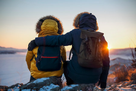 Romantic couple of tourists dressed in warm winter sportswear with tourist backpacks sitting in the...