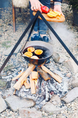 From above traditional mulled wine with slices of orange preparing in pot over burning logs in winter in countrysideの写真素材