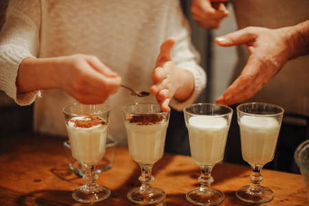 Family cooking homemade eggnog by the Christmas tree having fun. Beautiful woman and man with...